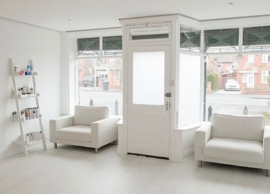 Bright, minimalist reception area at Bare Skin Clinic, Worsley, England, GB with cozy seating and natural light.
