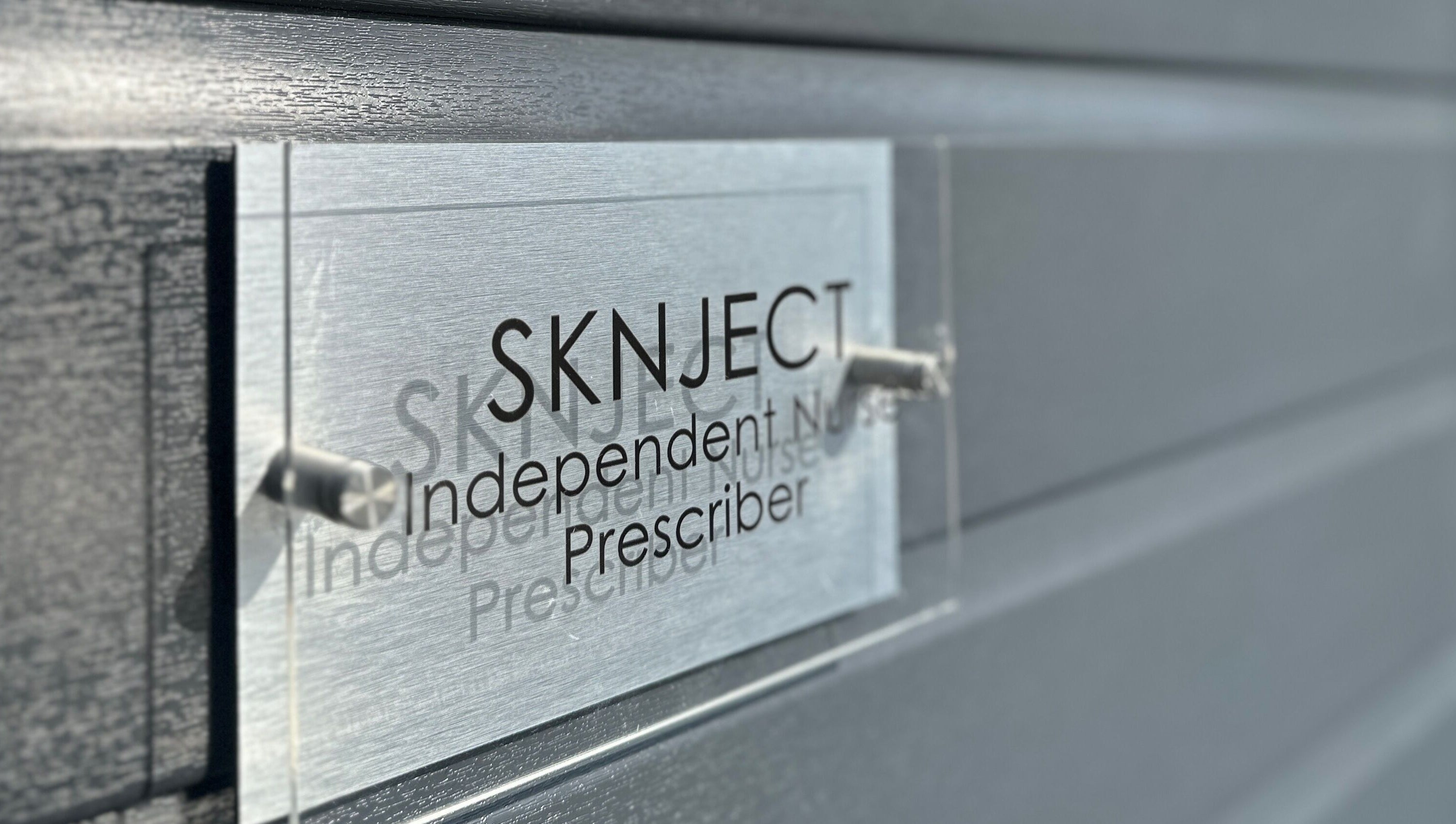 Sknject signage on a gray wall in Rotherham, England, GB, showcasing independent prescriber services.