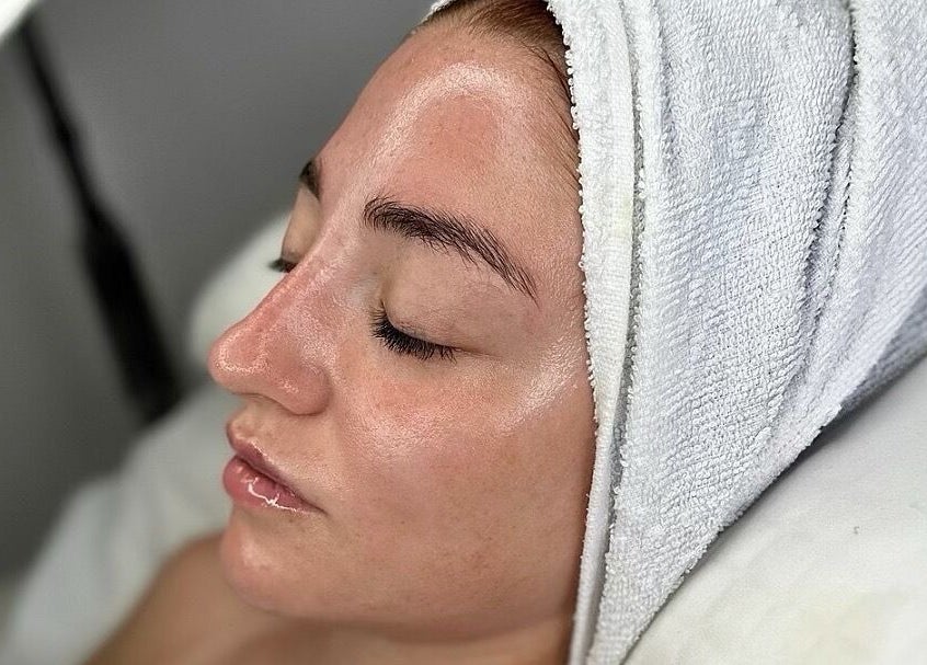 Relaxed woman in facial treatment at Sknject, Rotherham, England, GB with a towel wrap.