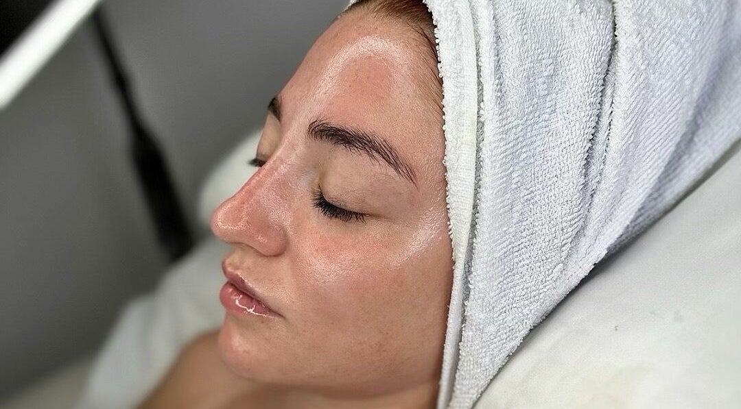 Relaxed woman in facial treatment at Sknject, Rotherham, England, GB with a towel wrap.