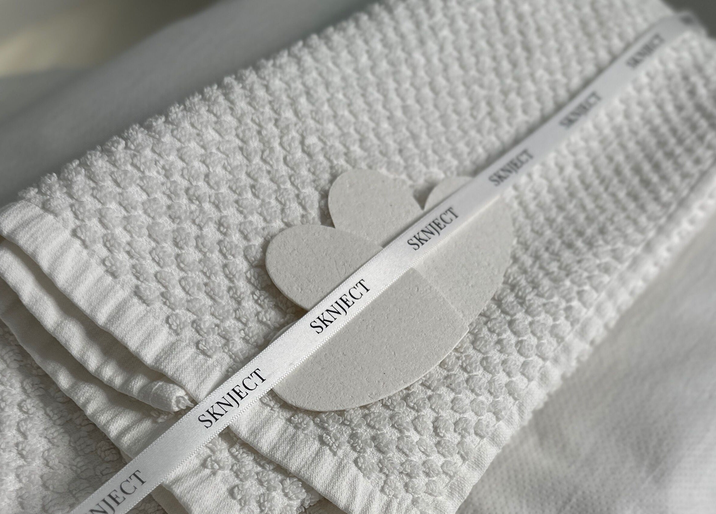 Elegant white towels with Sknject branding in Rotherham, England, GB, perfect for wellness services.