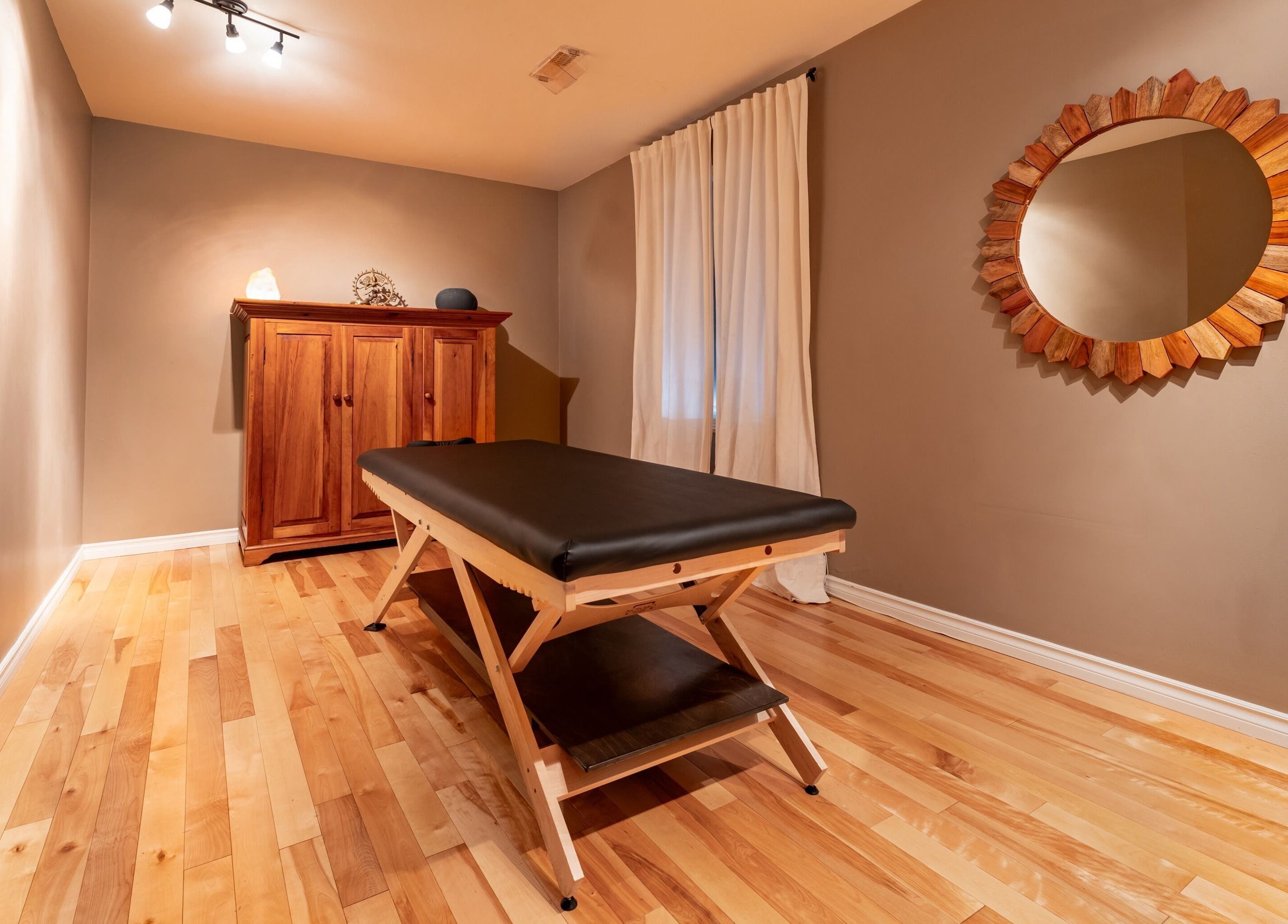 Salle de massage paisible chez Vibrations Om - Pointe-Claire, Québec, CA. Parquet clair et décor apaisant.