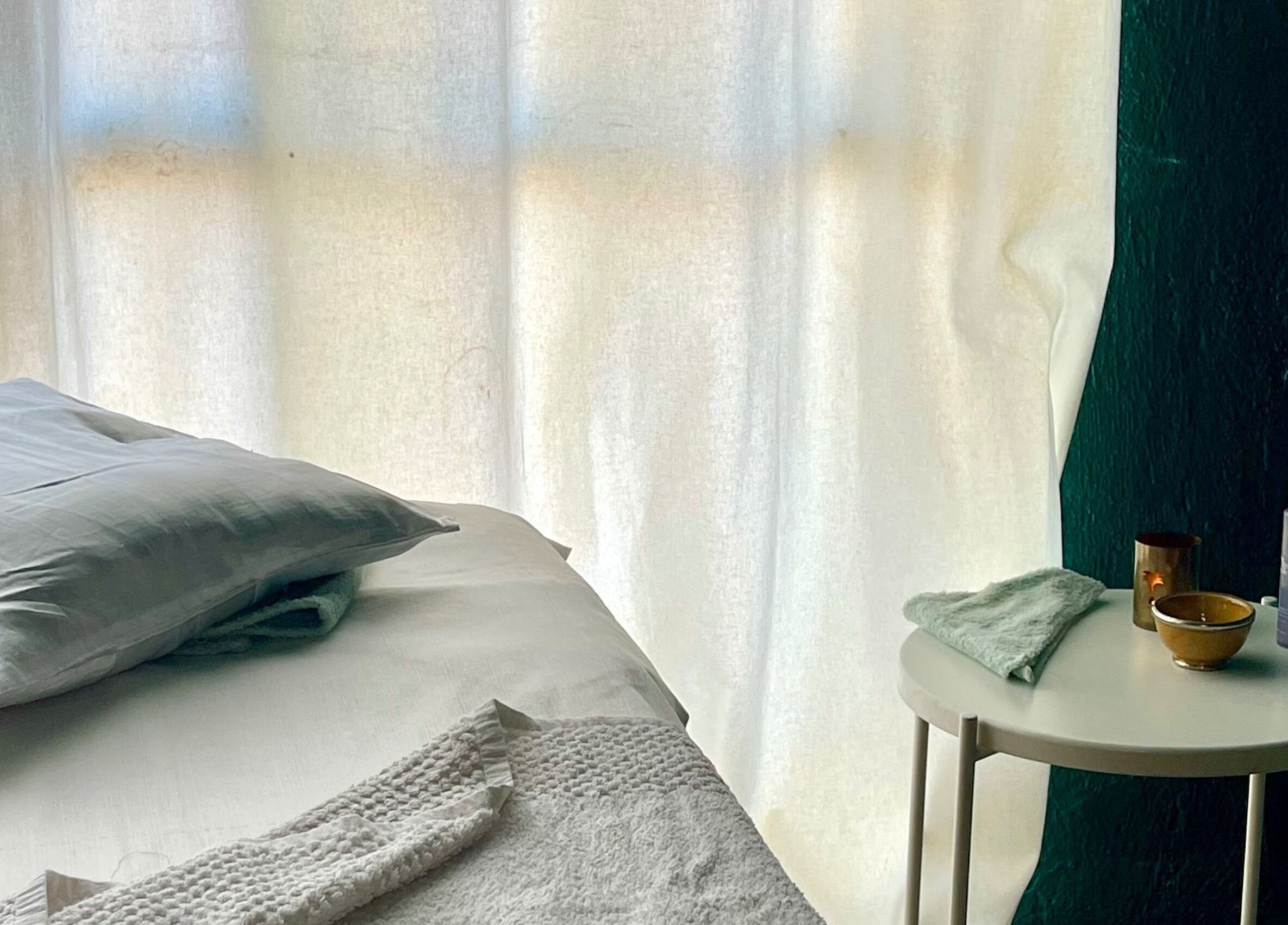 Cama de masaje en East Therapy, Barcelona, Catalunya, ES, con luz suave para una experiencia relajante.