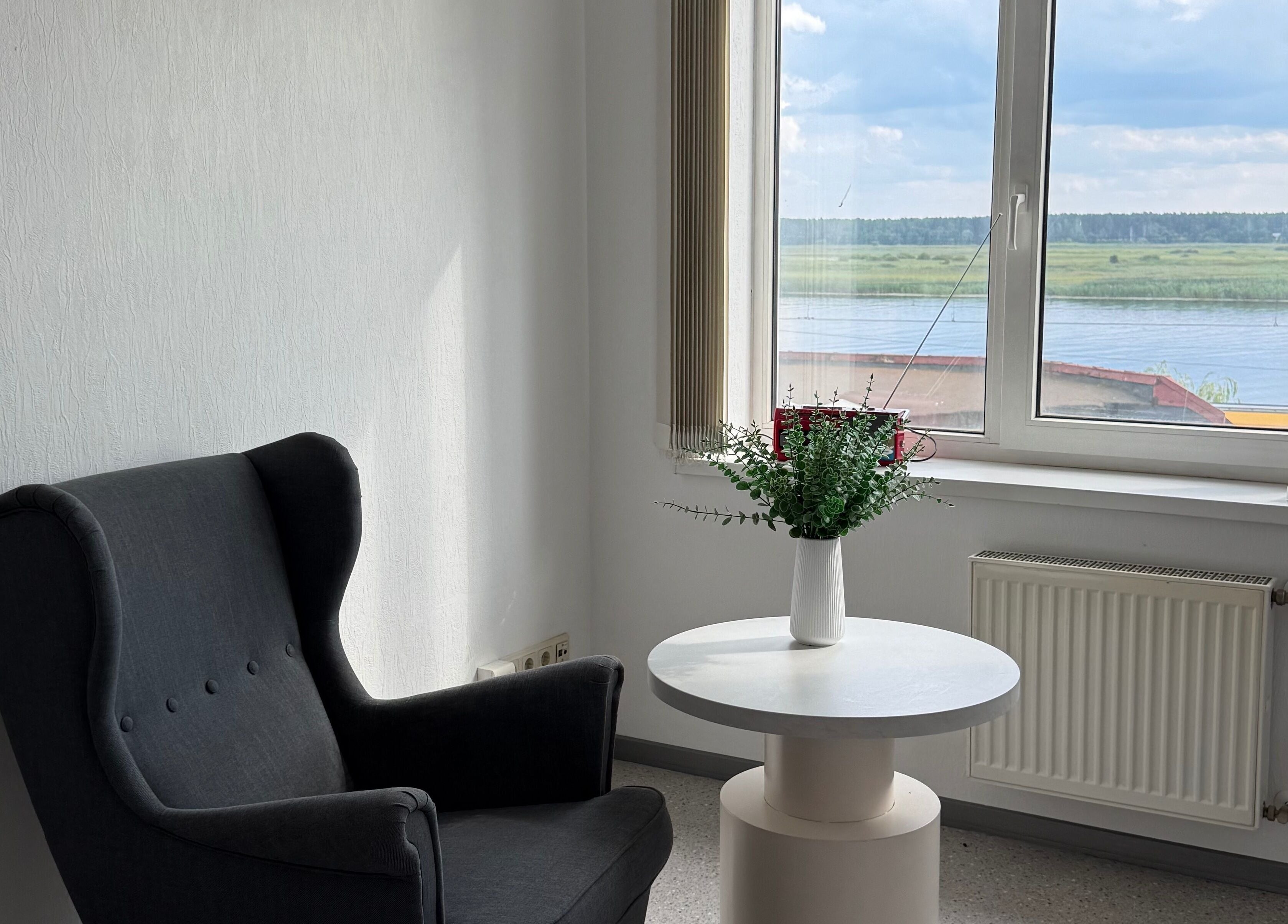 Cozy chair and table in natural light at Adelenailsstudio, Jūrmala, Latvija, LV, with scenic river view.