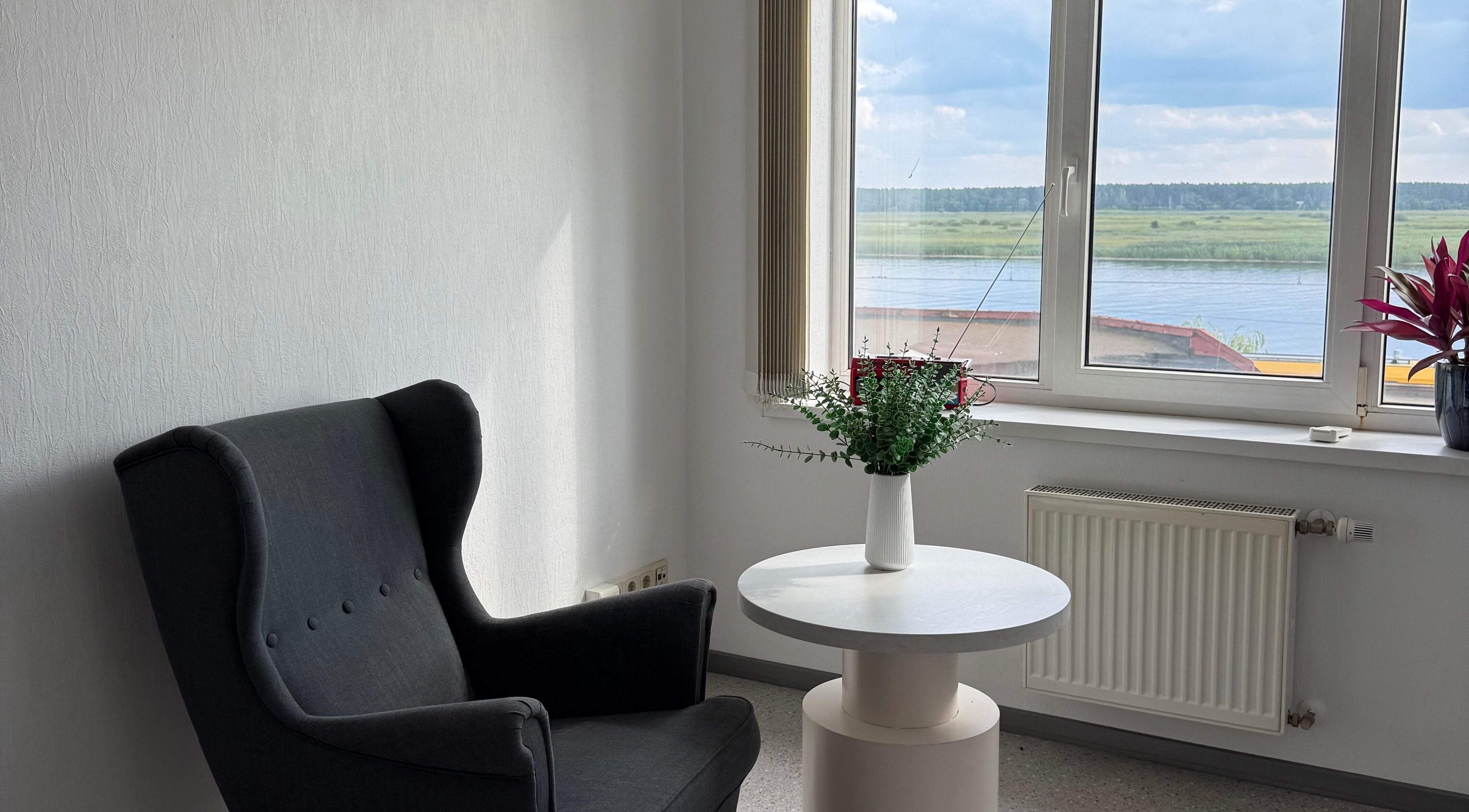 Cozy chair and table in natural light at Adelenailsstudio, Jūrmala, Latvija, LV, with scenic river view.