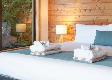 Cozy spa room at Kimi Ora Day Spa in Kaiteriteri, Tasman, NZ featuring a bed with fresh towels and wood-panel walls.