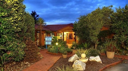 Entrance to Kimi Ora Day Spa, surrounded by lush greenery, Kaiteriteri, Tasman, NZ at twilight.