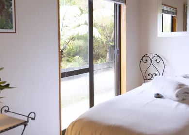 Tranquil massage room at Kimi Ora Day Spa, Kaiteriteri, Tasman, NZ, featuring a plush bed and garden view.