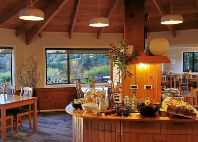 Inviting dining area at Kimi Ora Day Spa in Kaiteriteri, Tasman, NZ, with scenic views and cozy wooden decor.