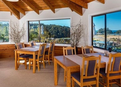 Sunny dining area at Kimi Ora Day Spa, Kaiteriteri, Tasman, NZ, overlooking lush greenery and beach.