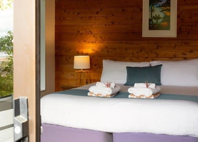 Serene bedroom view at Kimi Ora Day Spa, Kaiteriteri, Tasman, NZ, showcasing comfortable bedding and calming decor.