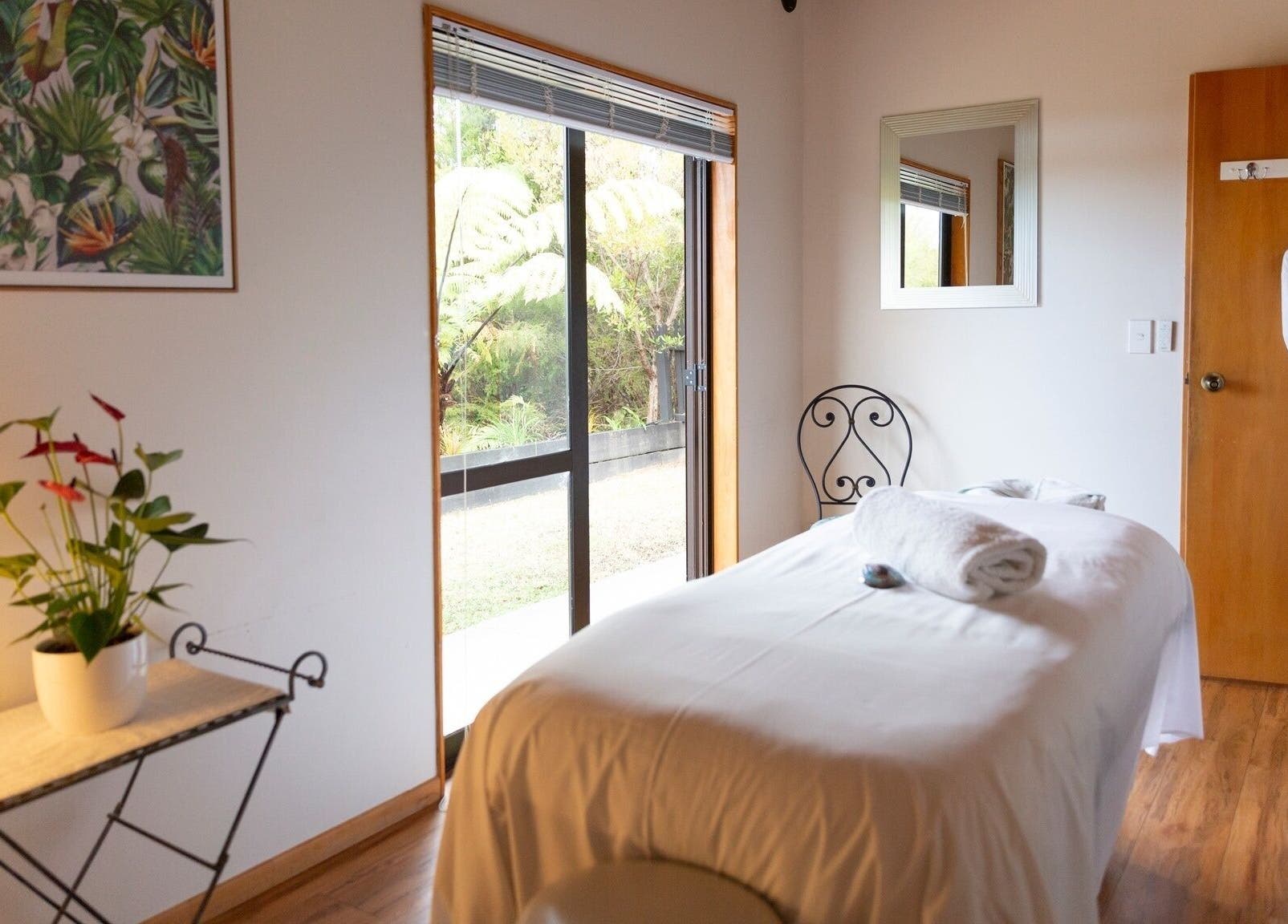 Tranquil spa room at Kimi Ora Day Spa in Kaiteriteri, Tasman, NZ, featuring massage bed and nature views.