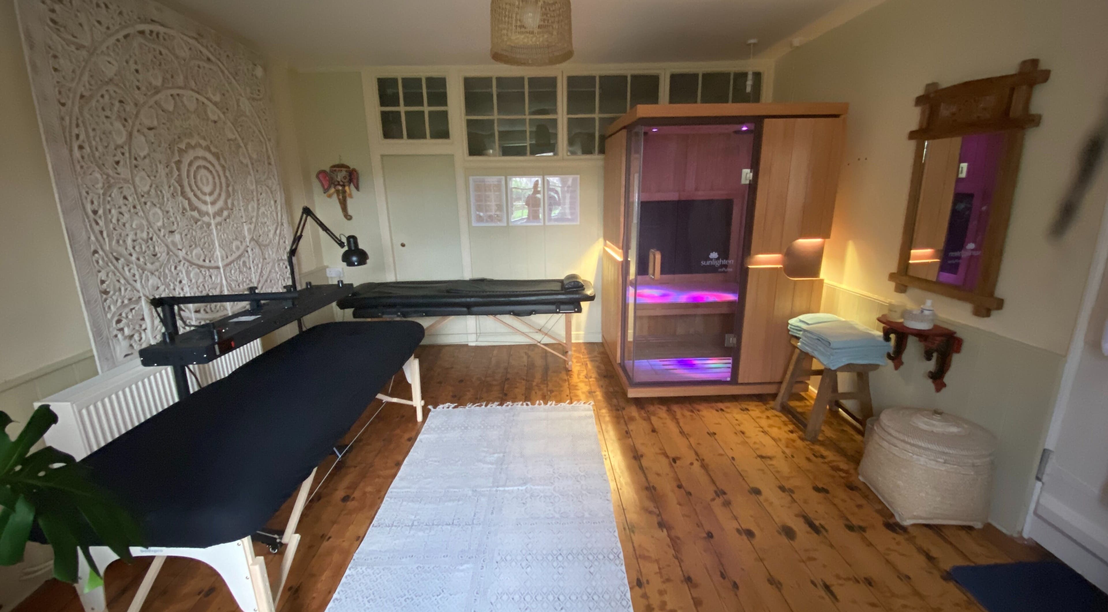 Sacred Sauna therapy room in Milverton, England, GB, featuring massage tables and a wooden sauna.