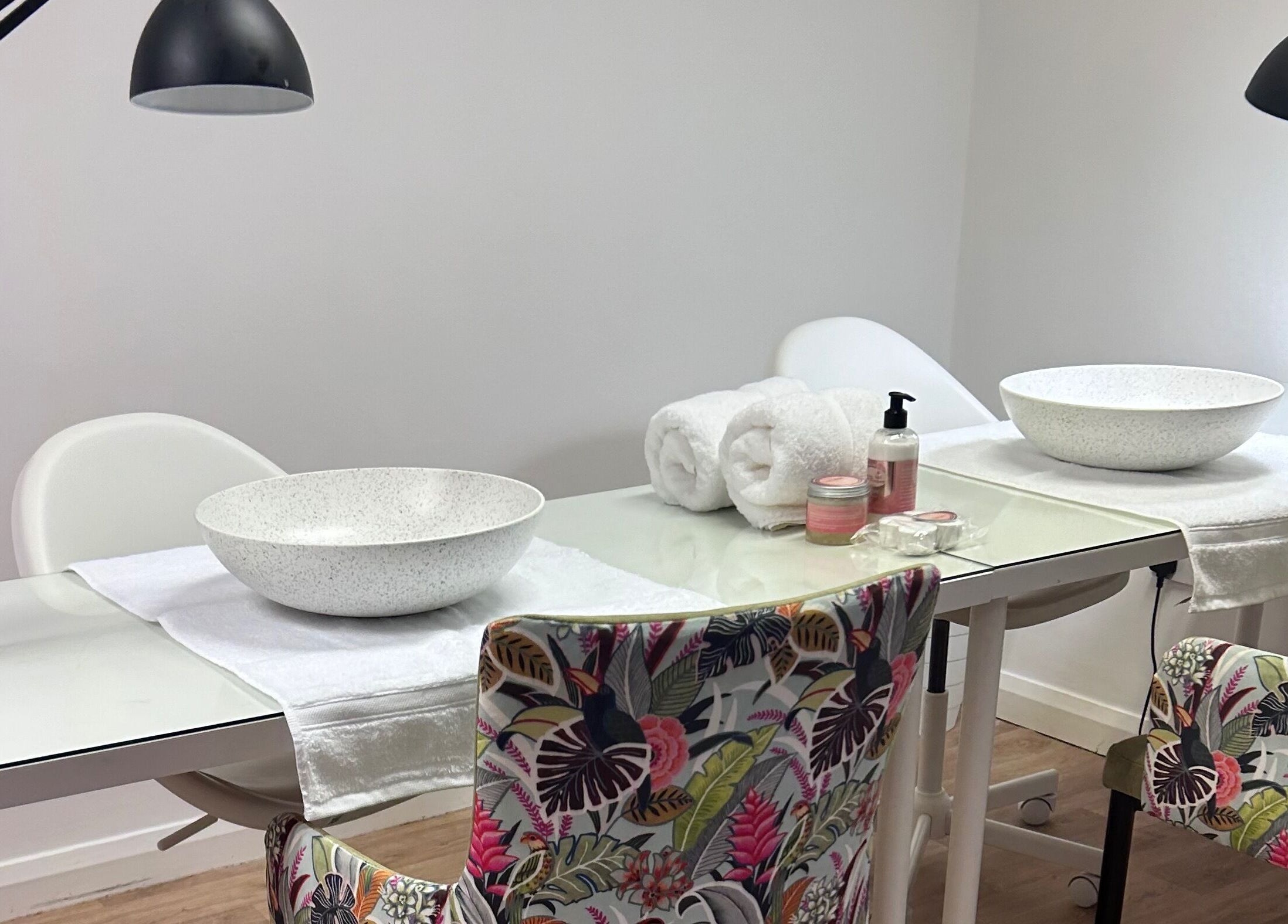 Nail stations at The Nail School, Middleton, England, GB, ready for treatment with bowls, towels, and products.