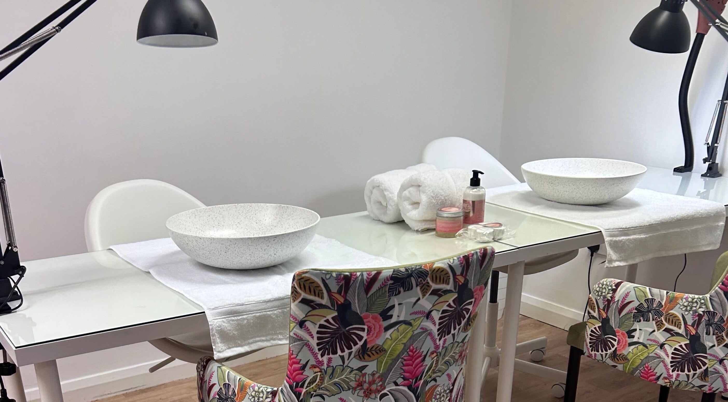 Nail stations at The Nail School, Middleton, England, GB, ready for treatment with bowls, towels, and products.