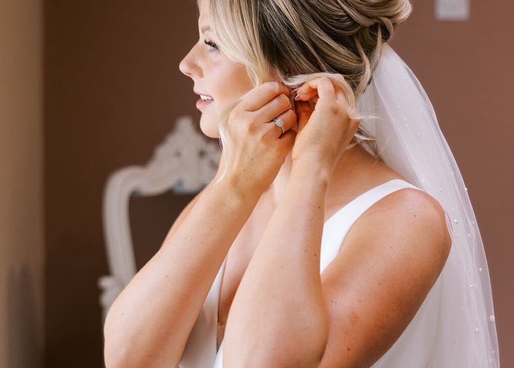 Bride adjusting earrings at G L O Y À, Rochester, England, GB. Serene ambiance for weddings.