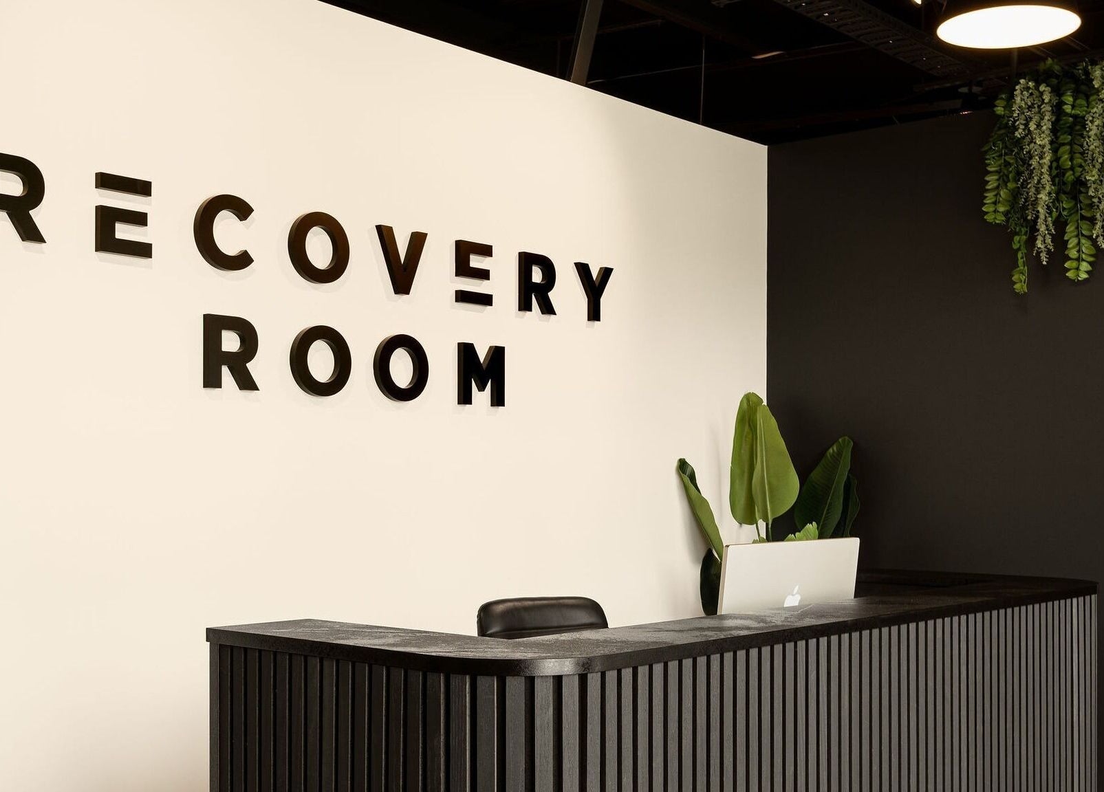 Stylish reception at Recovery Room Sippy Downs, Queensland, AU with modern decor and green plants.