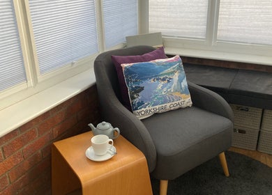 Relaxing corner at Sarah Sharp Massage, Copmanthorpe, England, with a plush chair and a warm cup of tea.