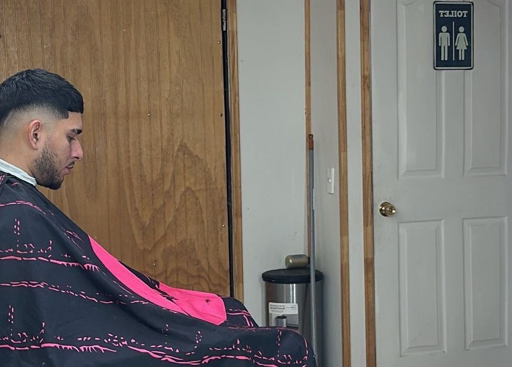 Man getting a haircut at Yeyo Barber Studio, Valdivia, Los Ríos, CL near a restroom door.