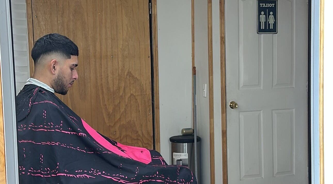 Man getting a haircut at Yeyo Barber Studio, Valdivia, Los Ríos, CL near a restroom door.