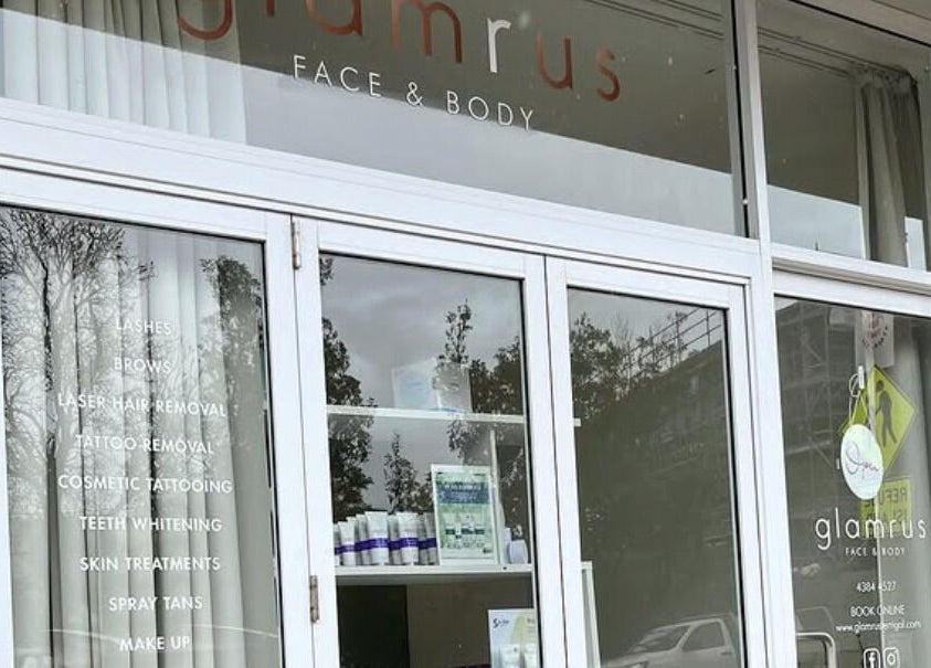Front entrance of Glam R Us Face and Body, Terrigal, NSW, showcasing beauty services list.