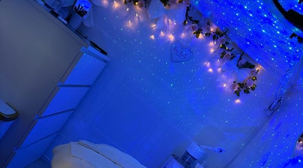 Tranquil blue-lit room at Bows Beauty & Aesthetics, Bognor Regis, England, GB, with star-like lights and floral decor.