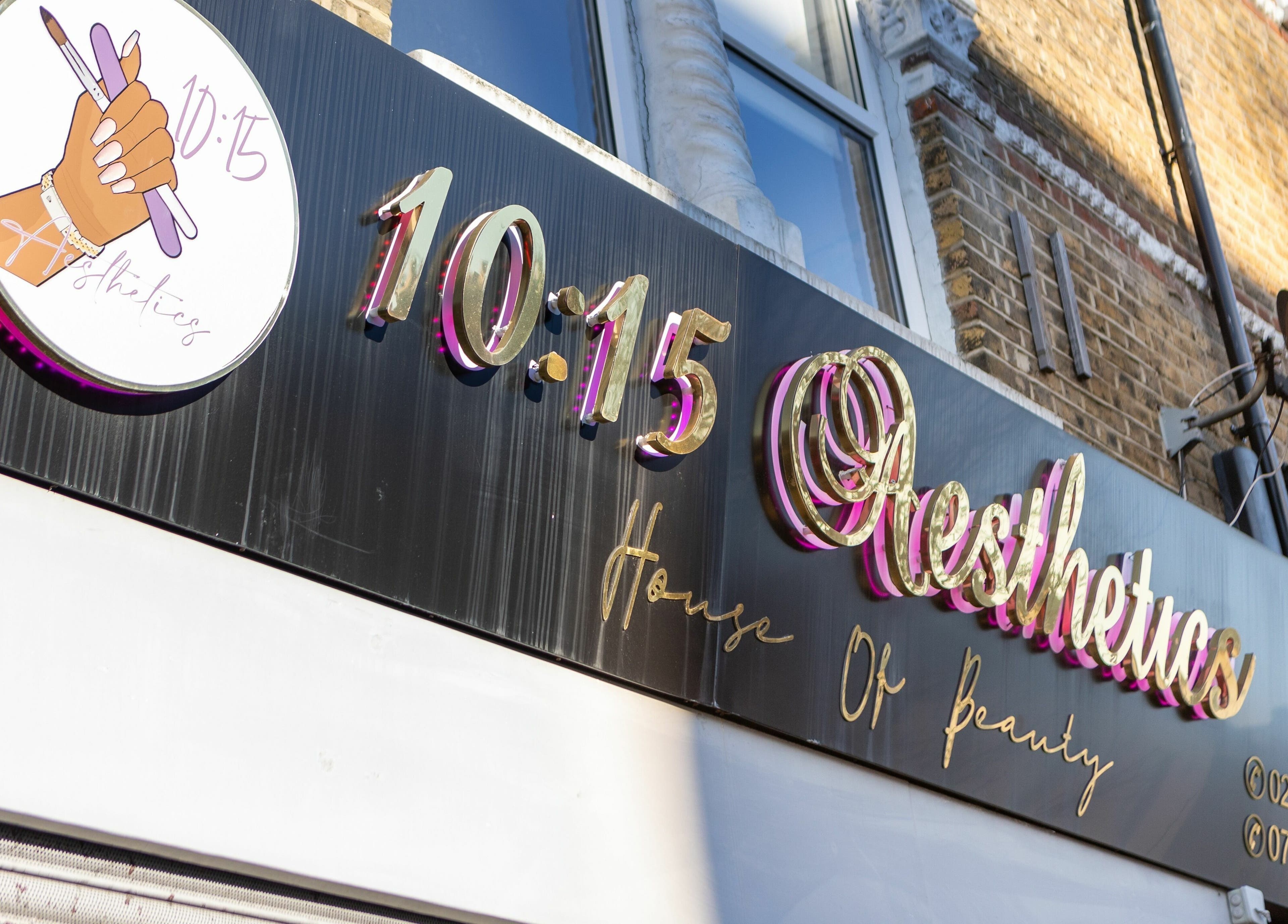 Signage of 10:15 Aesthetics in London, England, GB, featuring elegant gold lettering on a black background.