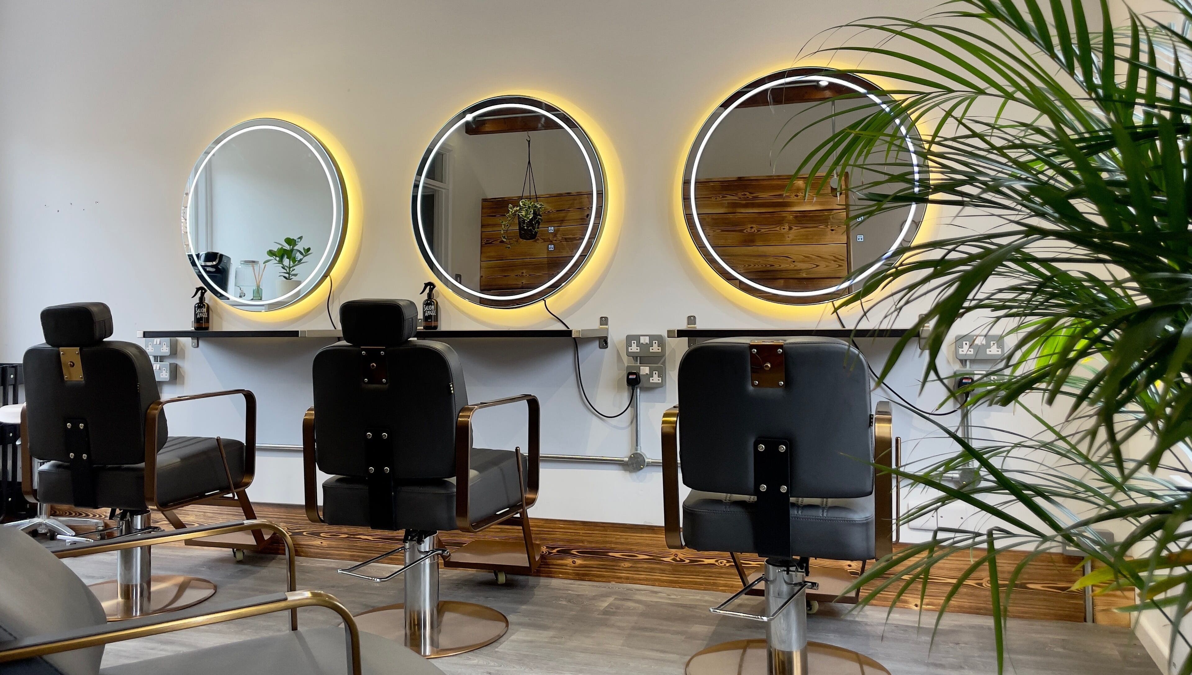 Chic salon interior at HAIR By Joshua Jones, Taunton, England, GB with modern chairs and illuminated mirrors.