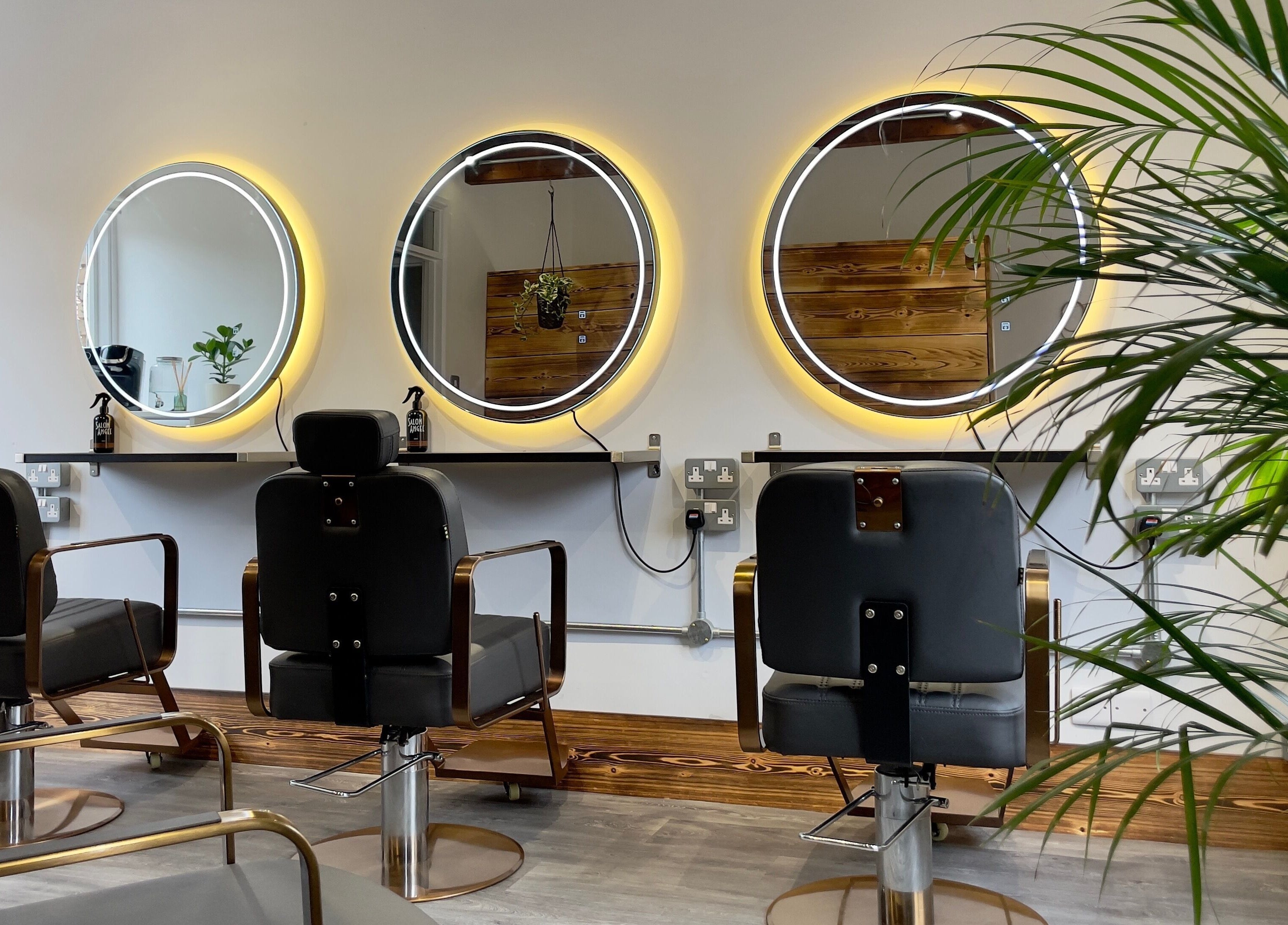 Chic salon interior at HAIR By Joshua Jones, Taunton, England, GB with modern chairs and illuminated mirrors.