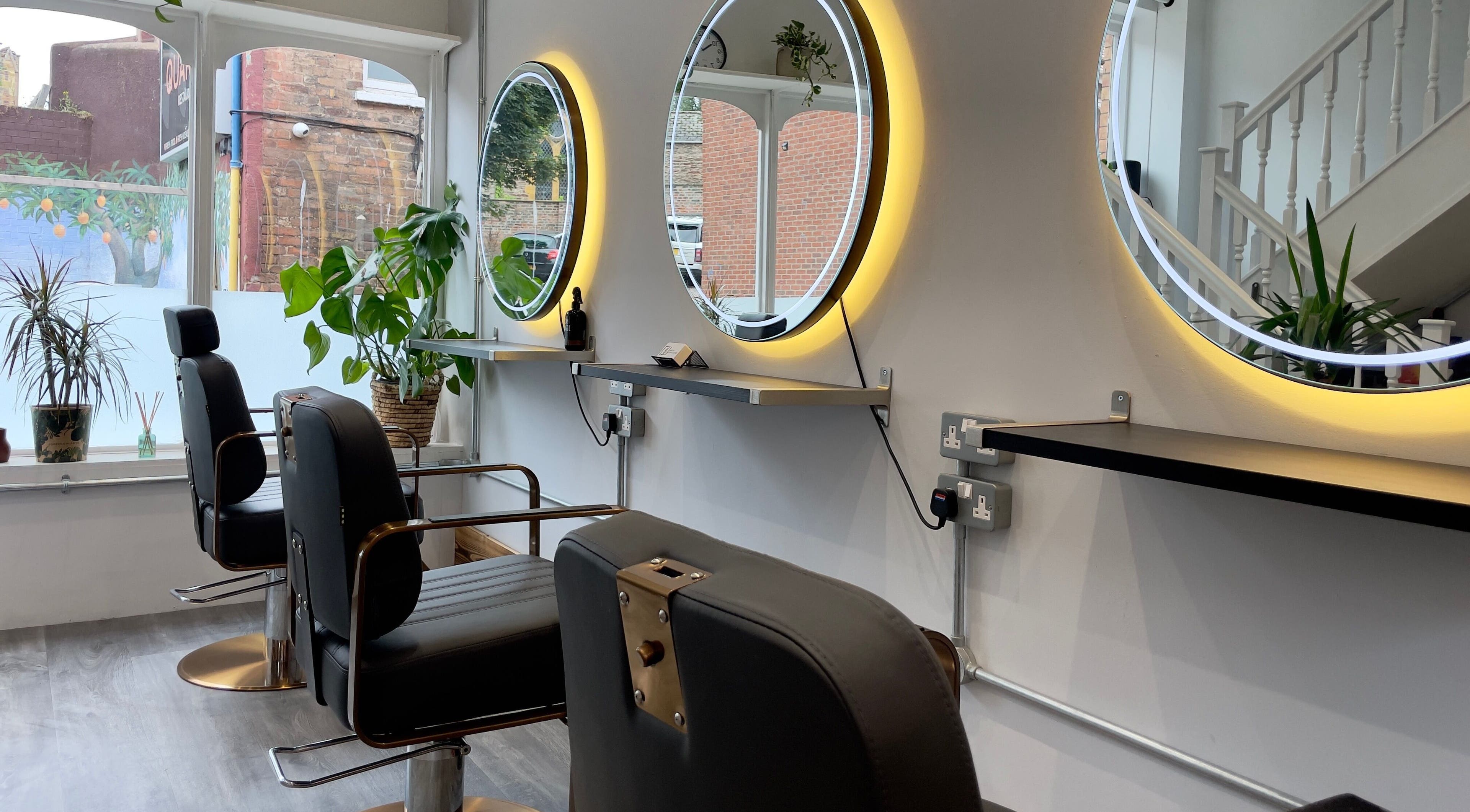 Modern salon interior with circular mirrors and stylish chairs at HAIR By Joshua Jones, Taunton, England, GB.