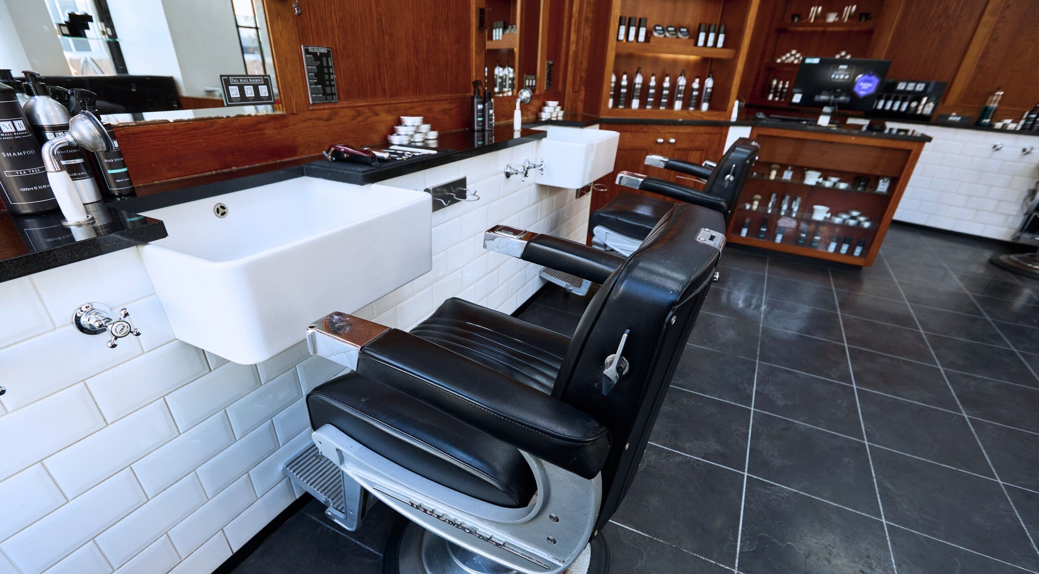 Interior view of Pall Mall Barbers Fitzrovia in London, England, GB featuring classic barber chairs and products.