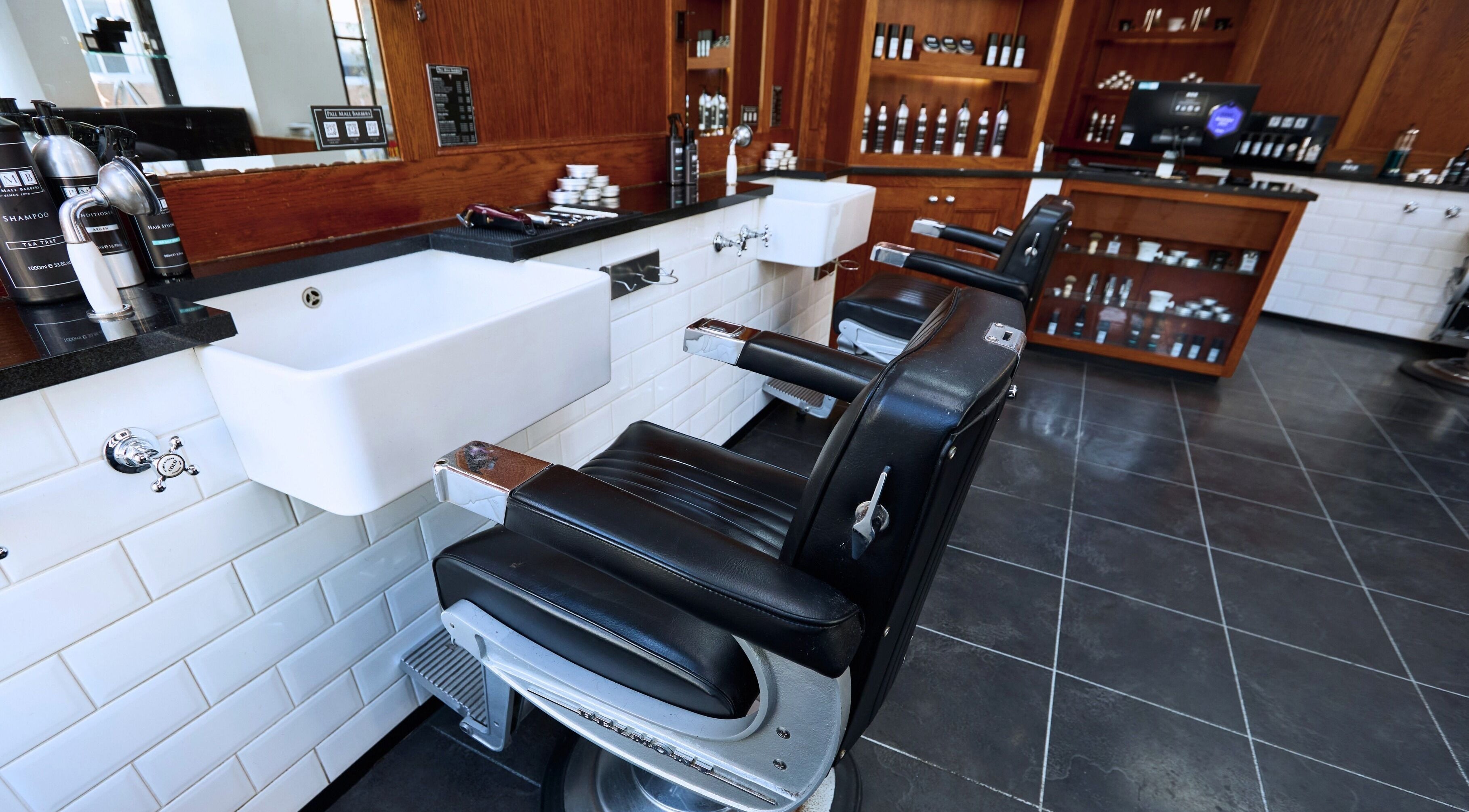 Interior view of Pall Mall Barbers Fitzrovia in London, England, GB featuring classic barber chairs and products.