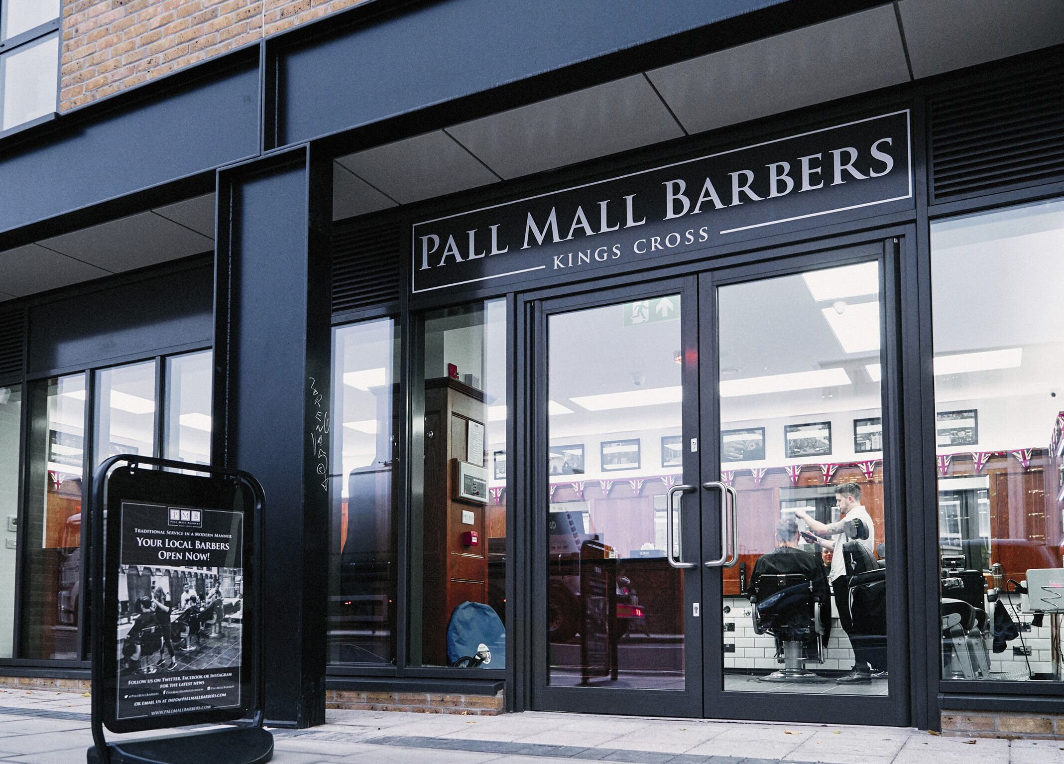 Front view of Pall Mall Barbers Kings Cross in London, England, GB with stylish glass doors.