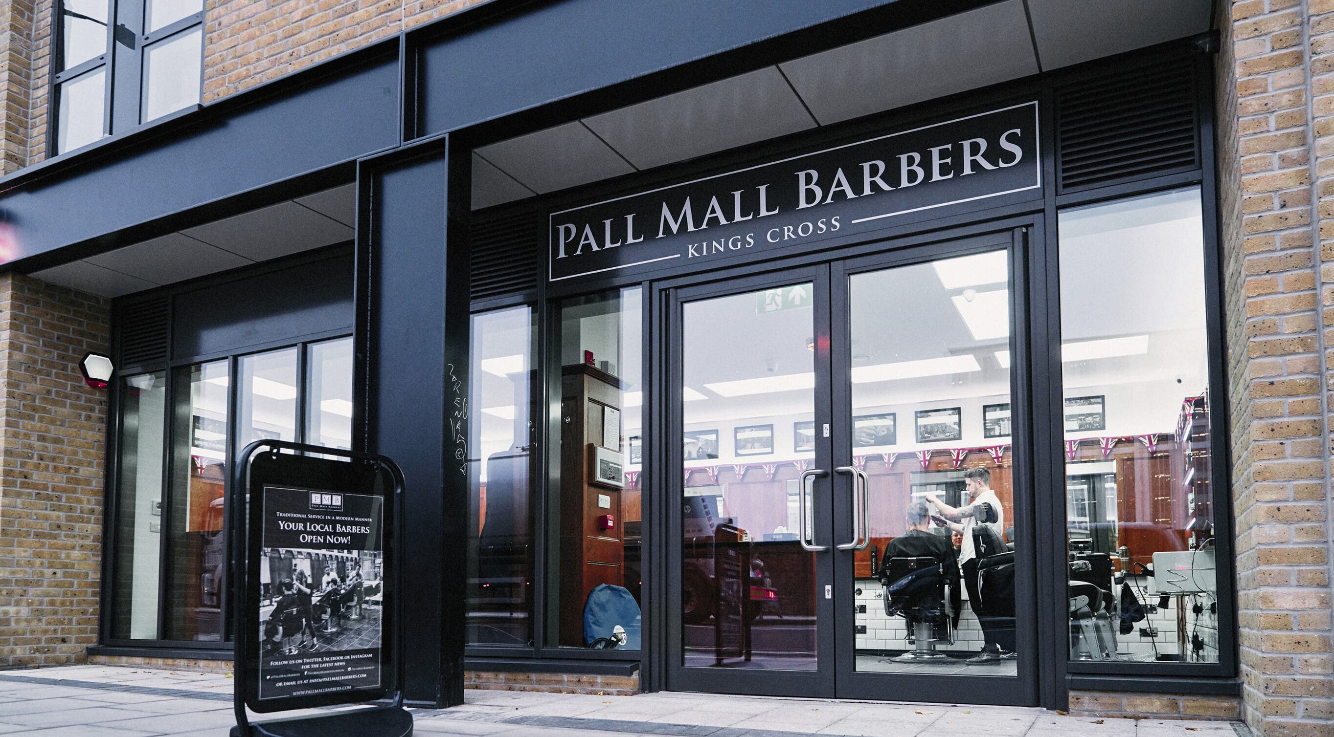 Front view of Pall Mall Barbers Kings Cross in London, England, GB with stylish glass doors.