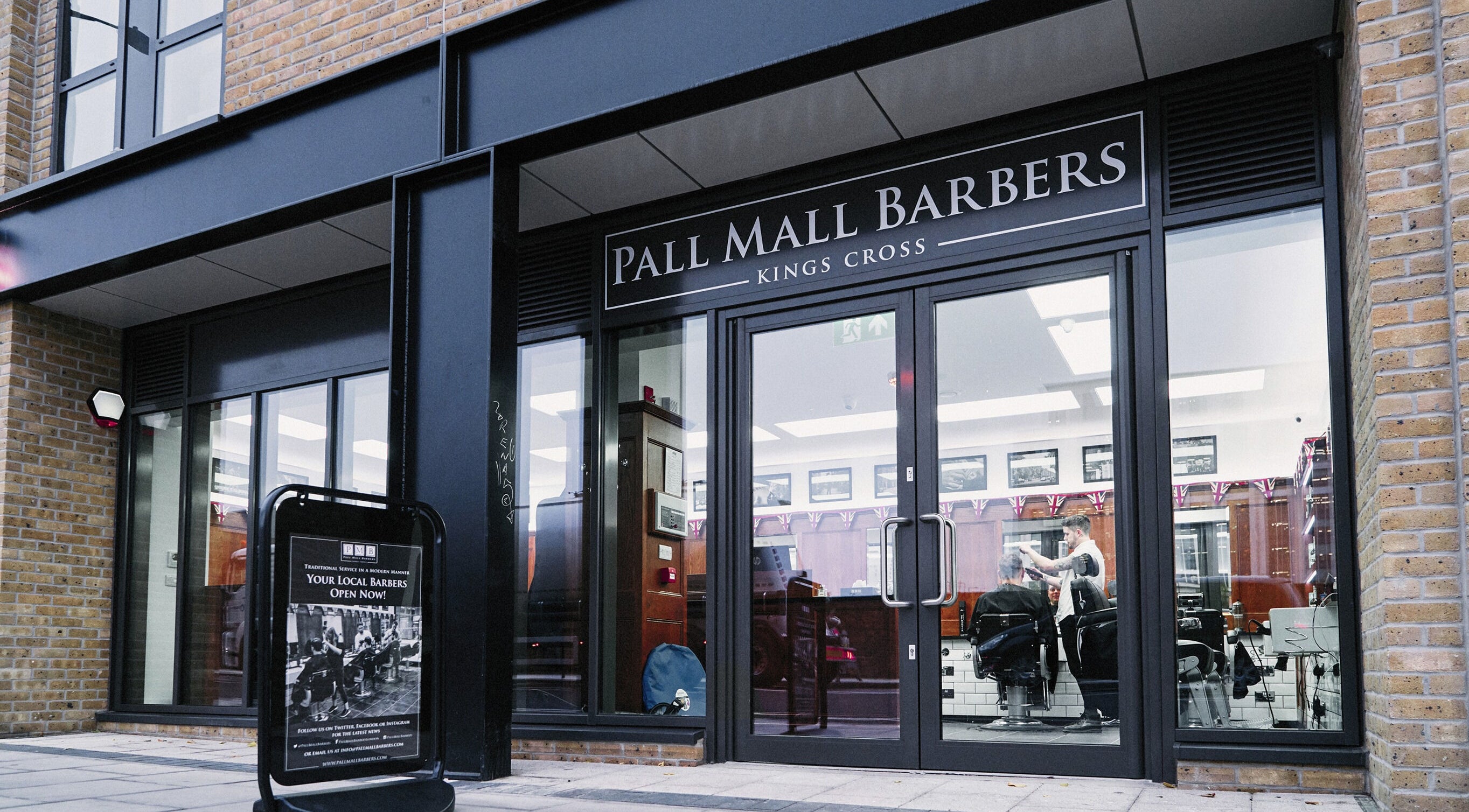 Front view of Pall Mall Barbers Kings Cross in London, England, GB with stylish glass doors.
