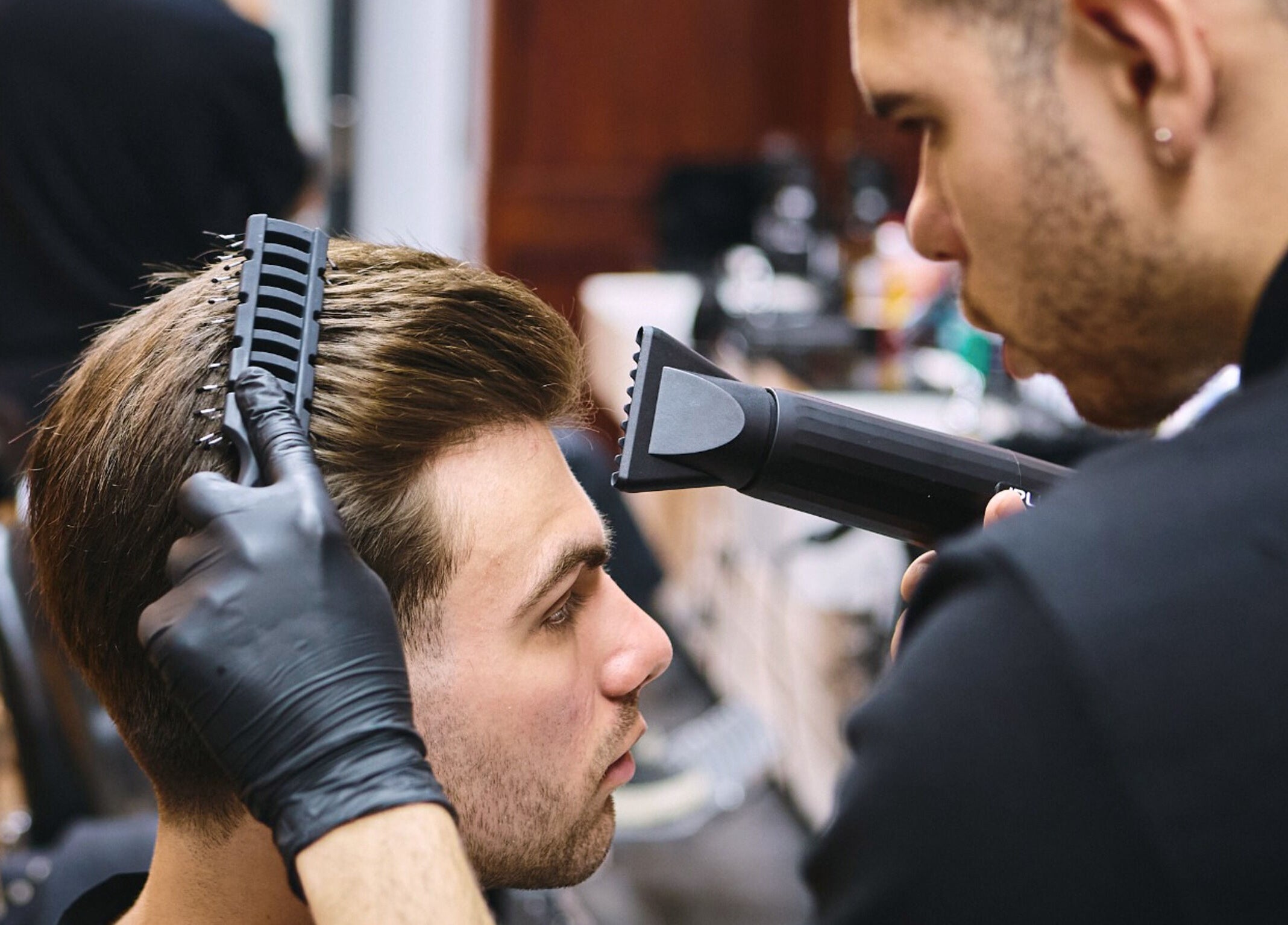 Barber styling hair at Pall Mall Barbers Kings Cross, London, England, GB. Professional grooming service.