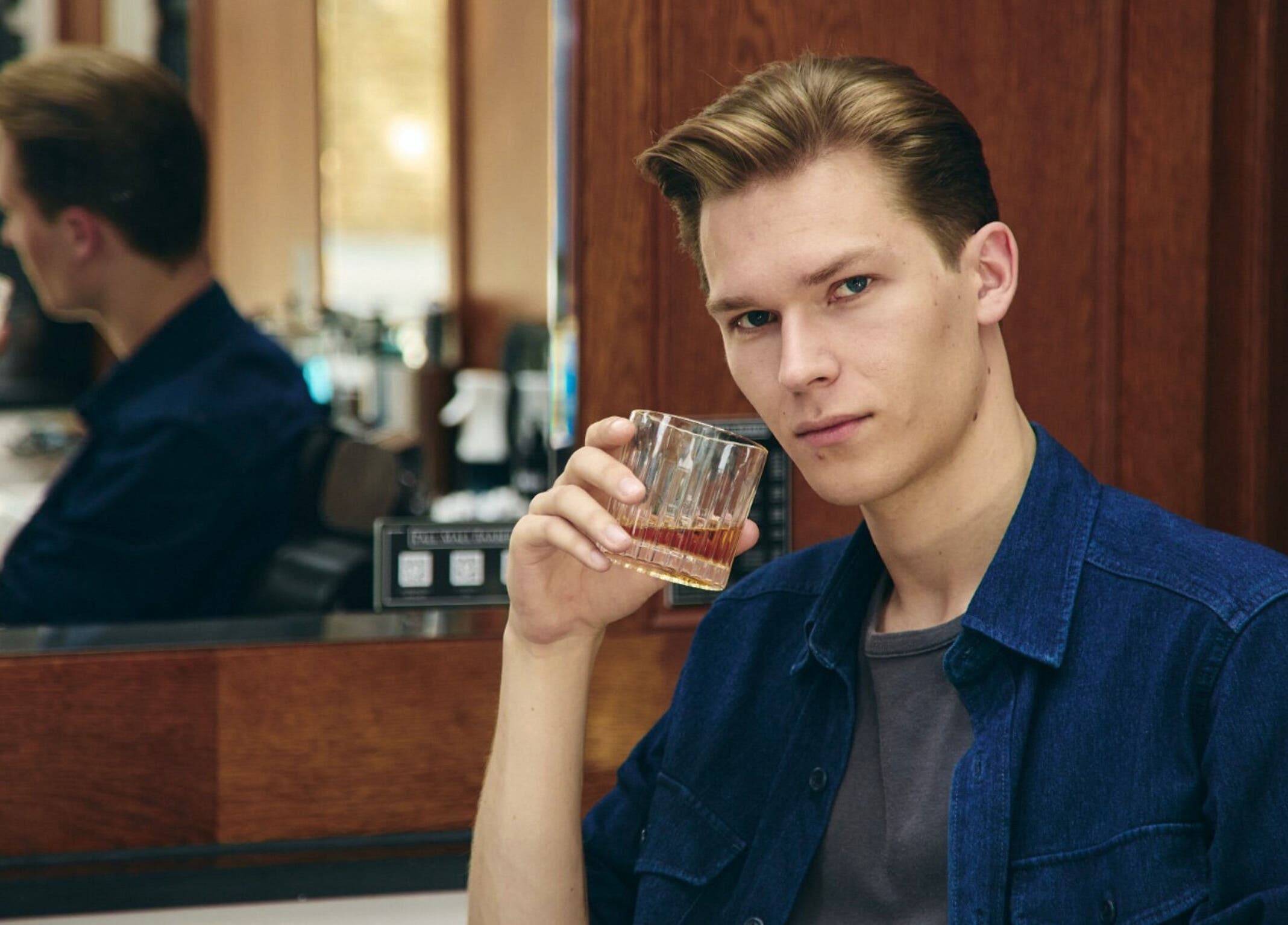 Gentleman enjoying a drink at Pall Mall Barbers Kings Cross, London, England, GB. Refined atmosphere and style.