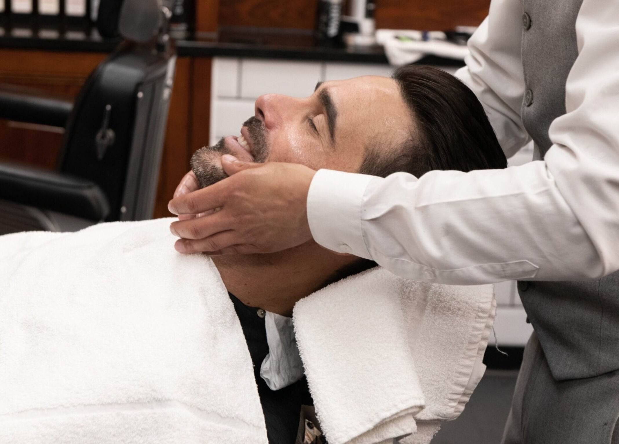 A client enjoys a relaxing shave at Pall Mall Barbers Kings Cross, London, England, GB.