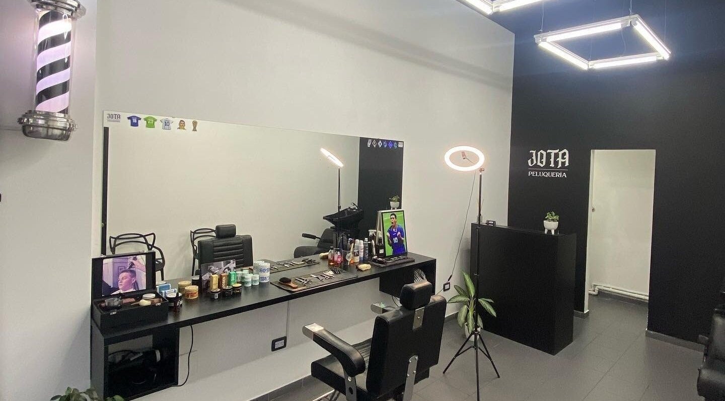 Interior de Jota Studio, Bahía Blanca, mostrando asientos de peluquería y productos organizados.