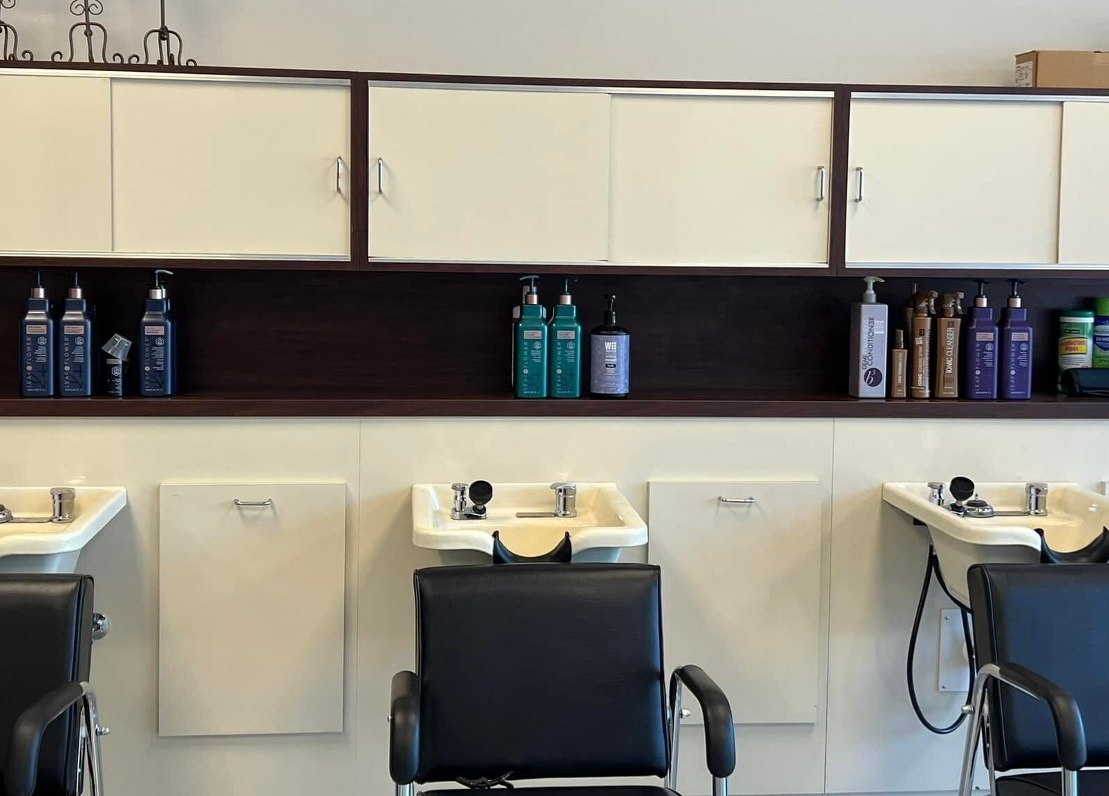 Shampoo stations at The A Salon and Spa in Lyman, South Carolina, US, featuring modern black chairs.