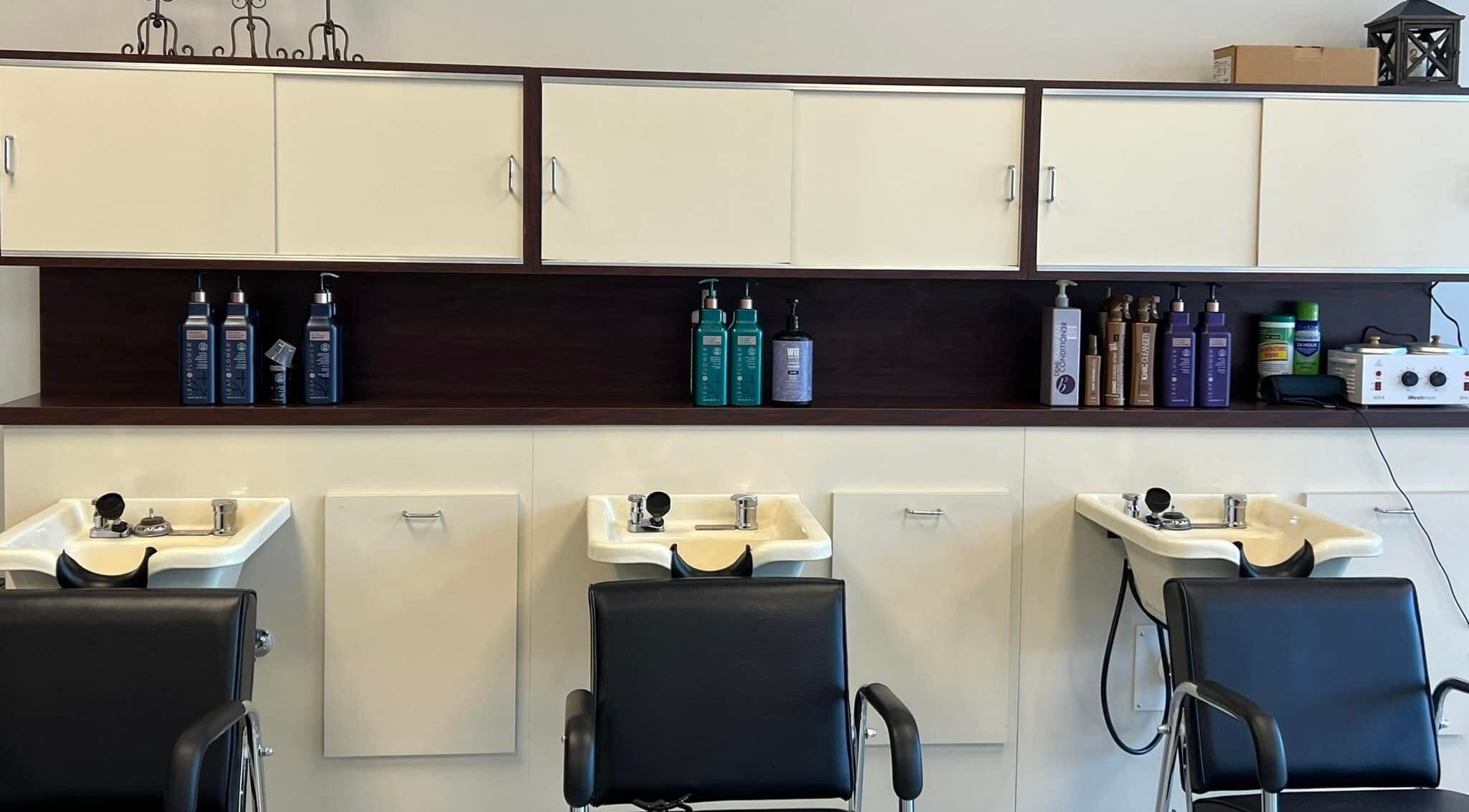 Shampoo stations at The A Salon and Spa in Lyman, South Carolina, US, featuring modern black chairs.
