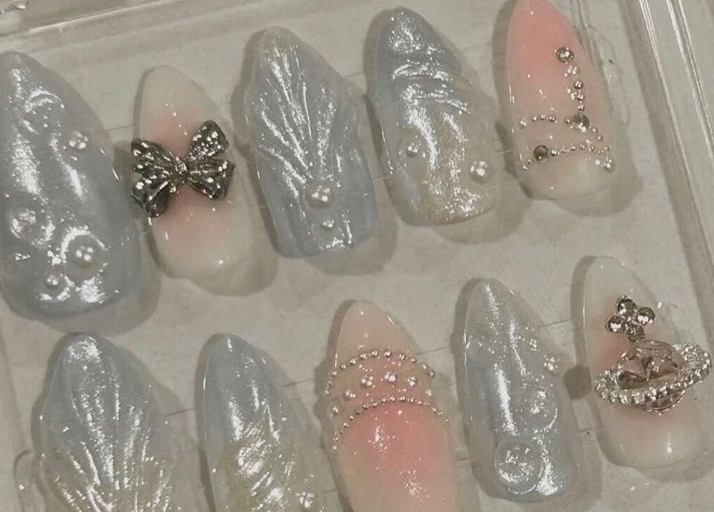 Elegant nail art designs at Nails By Hineni, Brambleton, Virginia, US, featuring pearly accents and metallic details.