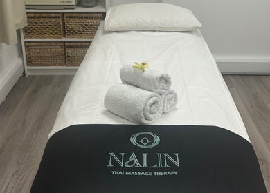 Massage bed at Nalin Thai Massage Therapy in Derby, England, GB with towels and orchid for relaxation.