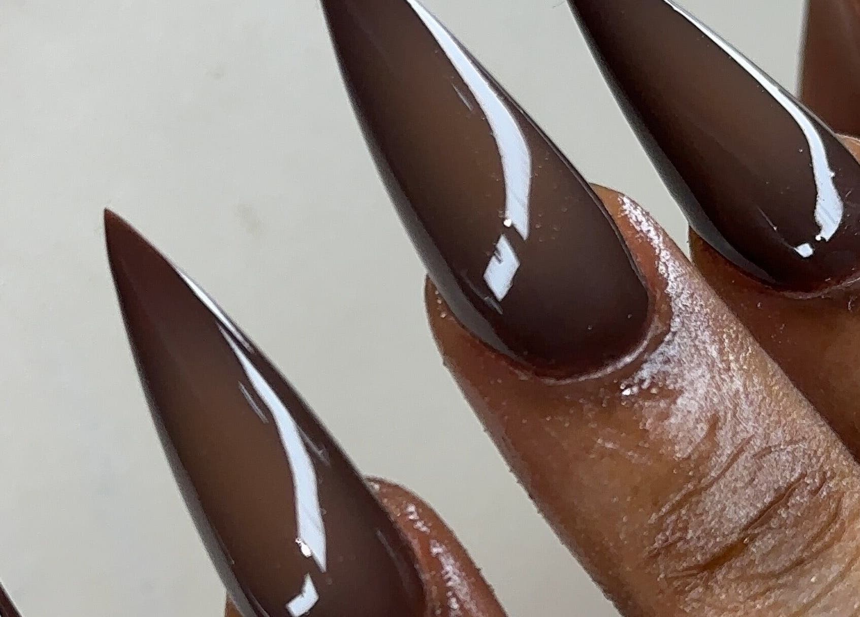 Elegant stiletto nails in dark brown at Nailglams ng, Abule Egba, Lagos, NG, showcasing expert nail art.