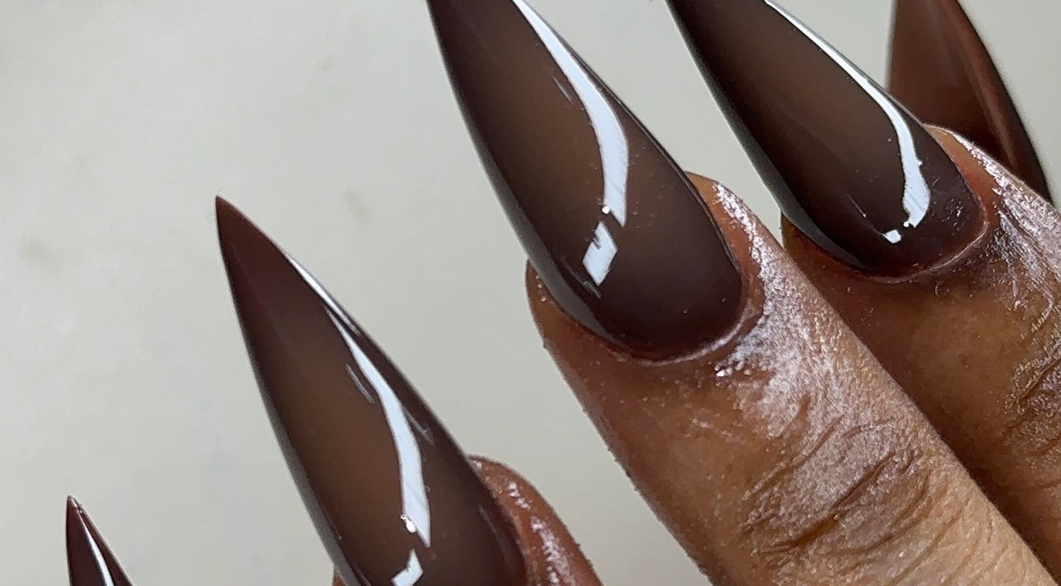 Elegant stiletto nails in dark brown at Nailglams ng, Abule Egba, Lagos, NG, showcasing expert nail art.