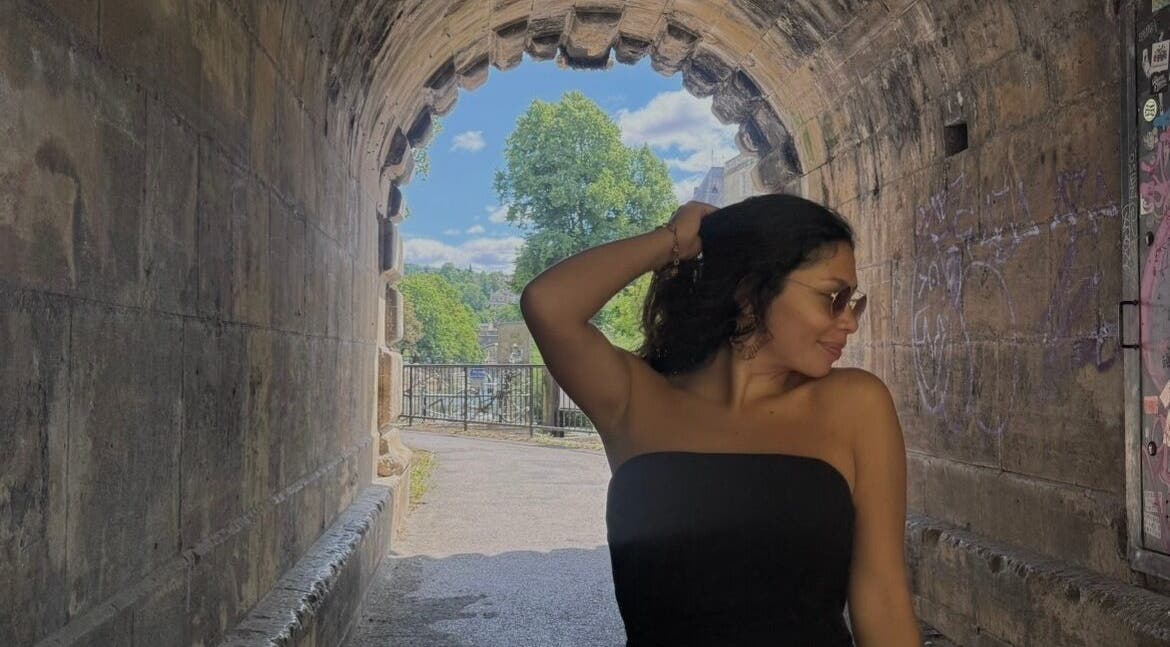 Woman in stylish attire poses gracefully in a stone tunnel near Raquel in Mosman, New South Wales, AU.