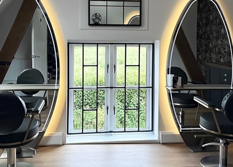 Sleek styling stations with oval mirrors at Anthony James, Pattingham, GB, create a modern and inviting salon atmosphere.