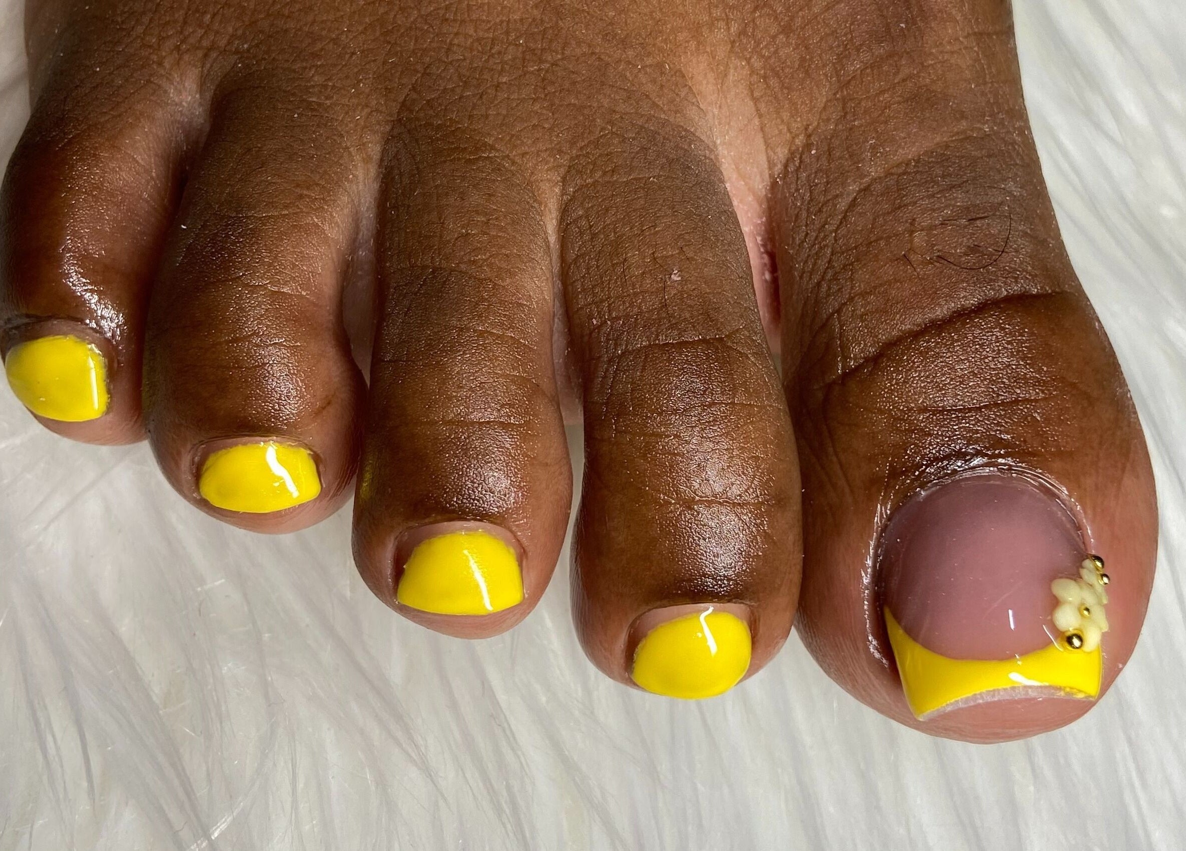 Bright yellow pedicure at For Love & Lemons | The Nail Studio, Saint Philip, BB. Intricate design on big toe.