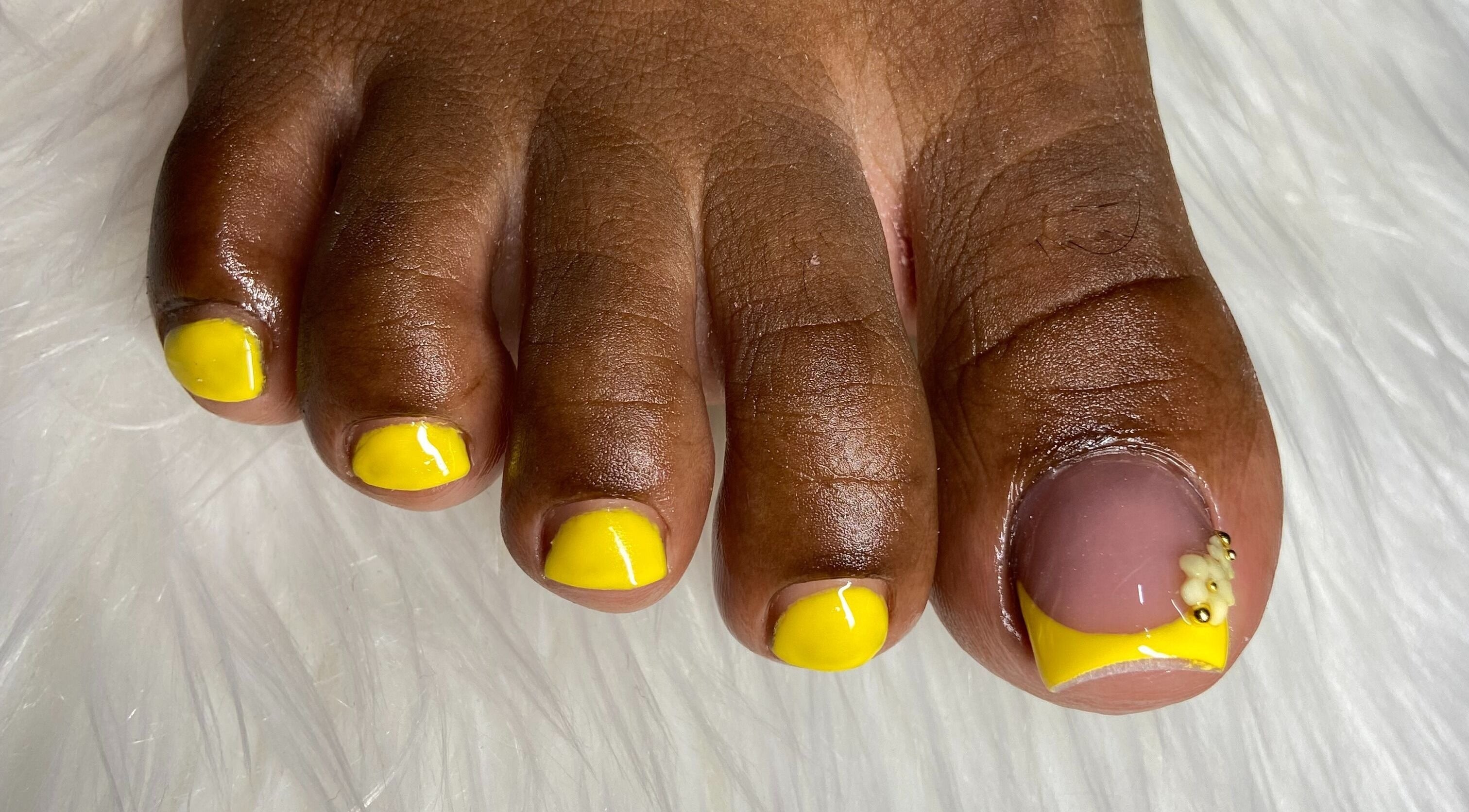 Bright yellow pedicure at For Love & Lemons | The Nail Studio, Saint Philip, BB. Intricate design on big toe.