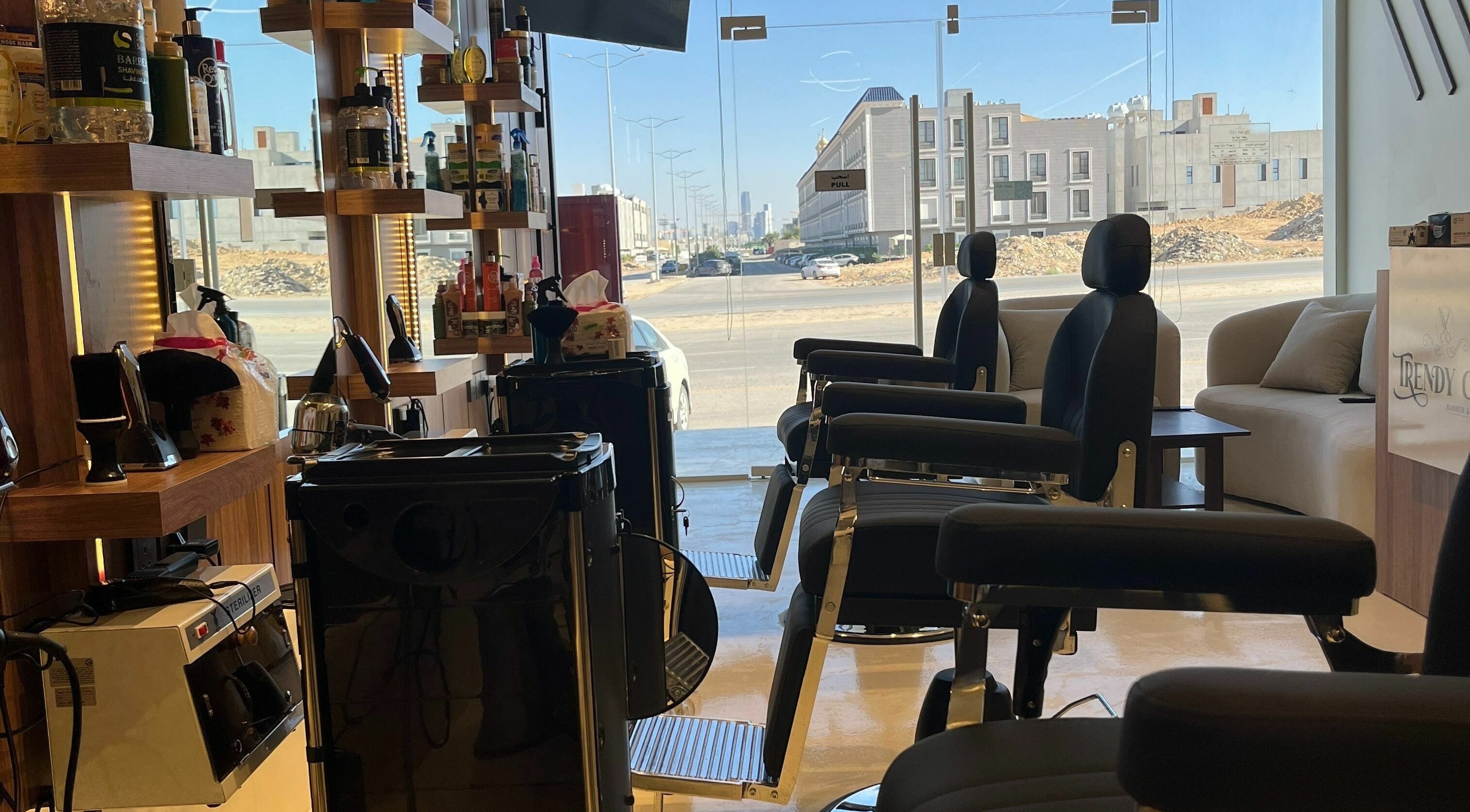 Modern decor of Trendy Cut | Al Qirawan in Riyadh, Riyadh Province, SA. Sleek chairs and stylish shelving enhance ambiance.